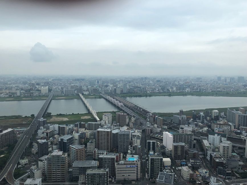 Gloomy aerial view of Osaka cityscape with multiple bridges crossing the river.