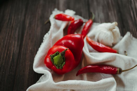 A still life composition of red peppers and garlic on a wooden table. Perfect for healthy eating themes.