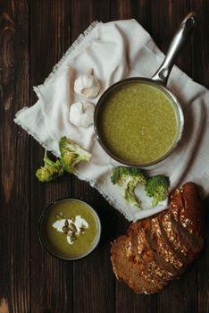 Warm broccoli soup served with seeded rustic bread on a wooden table.