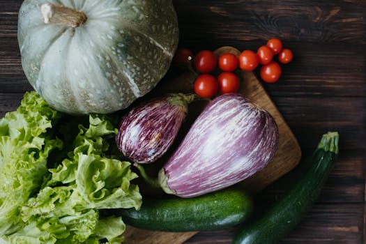 Close-up of assorted fresh vegetables including zucchini, lettuce, and tomatoes on a wooden board.