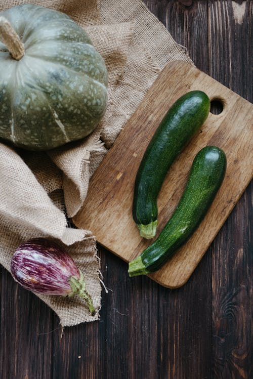 Free Zucchini on Wooden Chopping Board and Eggplant on Brown Wooden Table Stock Photo