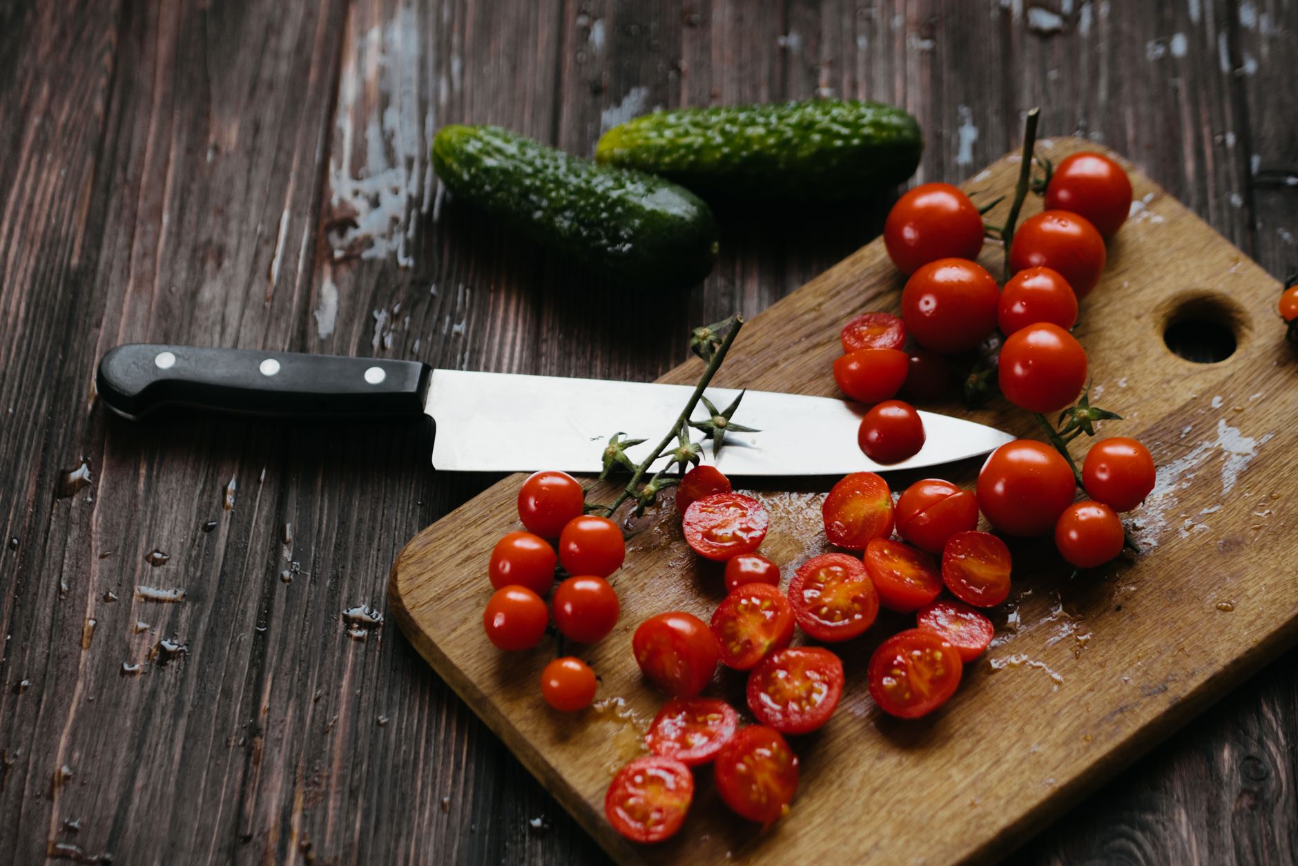 Various kitchen knives arranged for tomato prep
