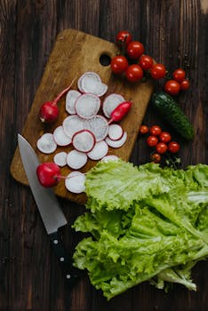 Top-down view of fresh radishes, cherry tomatoes, and lettuce on a cutting board.