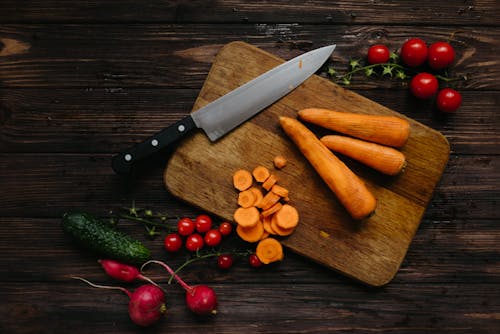 Sliced and Whole Carrots on Brown Wooden Chopping Board