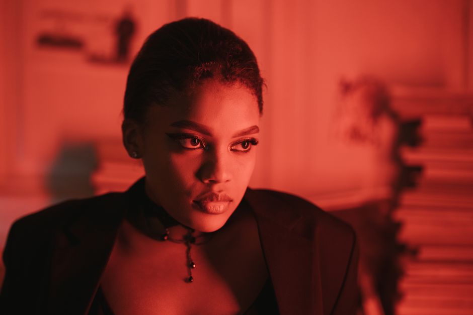 Fashion portrait of a woman with dramatic red lighting, exuding elegance and intensity.