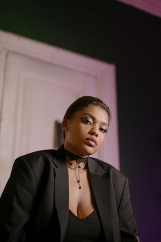 Portrait of an elegant woman in a black blazer and necklace exuding confidence indoors.
