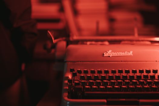 Close-up of an antique typewriter in a dim red-lit room, evoking a retro feel.