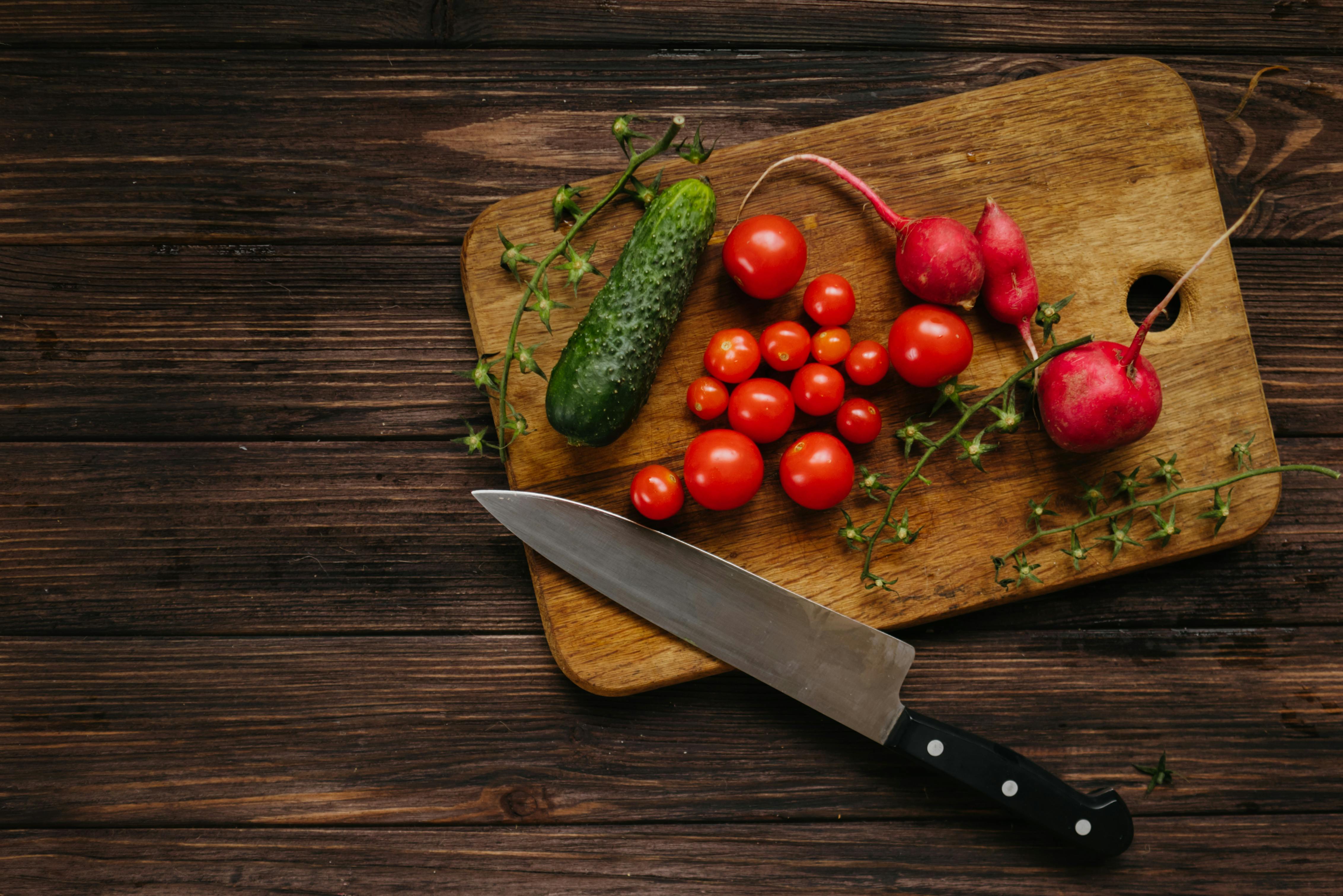 Fish fillet on a cutting Board with a knife, spices, oil and tomatoes on a  branch. Stock Photo by Artem_ka2