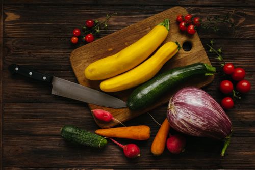 Free Top view of assorted fresh vegetables on a wooden cutting board with a kitchen knife. Stock Photo