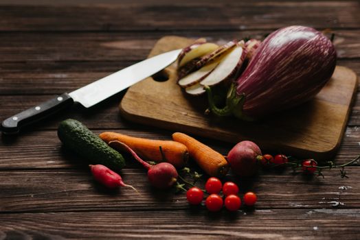 Colorful assortment of fresh vegetables on a wooden board with a knife, perfect for cooking.