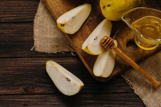 Fresh sliced pears with honey on a wooden board create a rustic healthy dining mood.