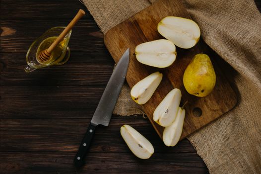 Top view of fresh sliced pears and honey on a wooden cutting board, perfect for healthy eating concepts.