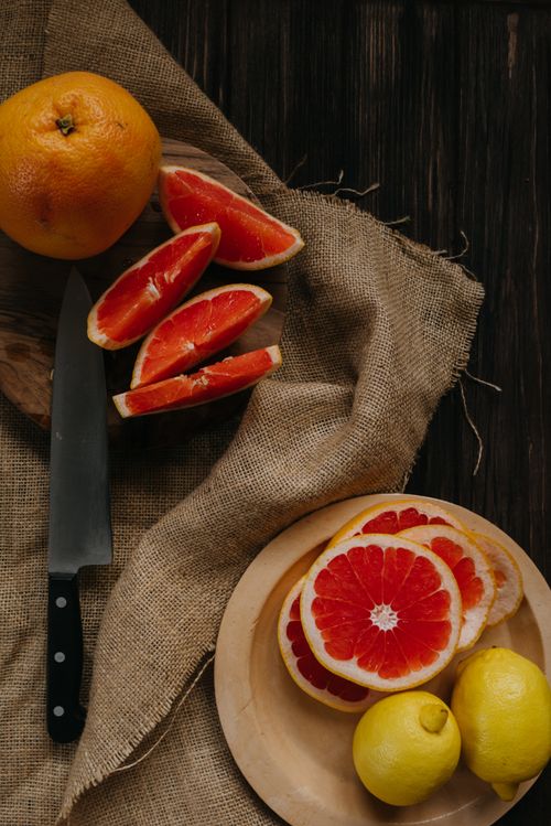 Free A rustic setup of sliced grapefruit and whole lemons on a wooden table, perfect for healthy eating themes. Stock Photo