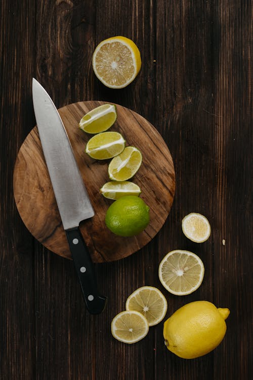 Sliced Lime and Black Handle Knife on Brown Wooden Chopping Board