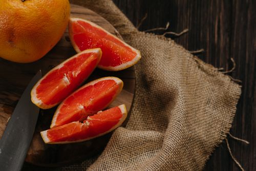 Free Close-up of fresh grapefruit slices on a rustic wooden board with burlap background. Stock Photo