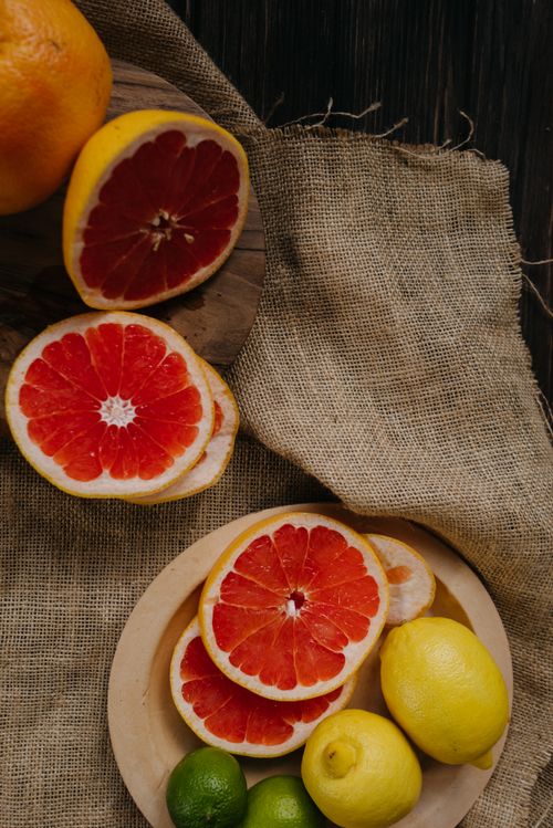 Free A vibrant display of sliced grapefruit, lemons, and limes on a woven fabric backdrop. Stock Photo