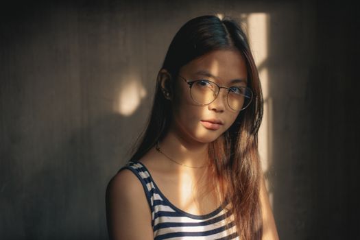 Serious teenage in eyeglasses in shadow