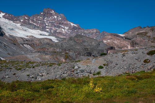Free Stunning view of a mountain range with glaciers, rocks, and green meadows under a clear blue sky. Stock Photo