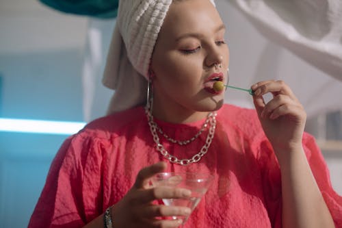 Woman with Her Hair in a Towel Eating an Olive from a Cocktail 