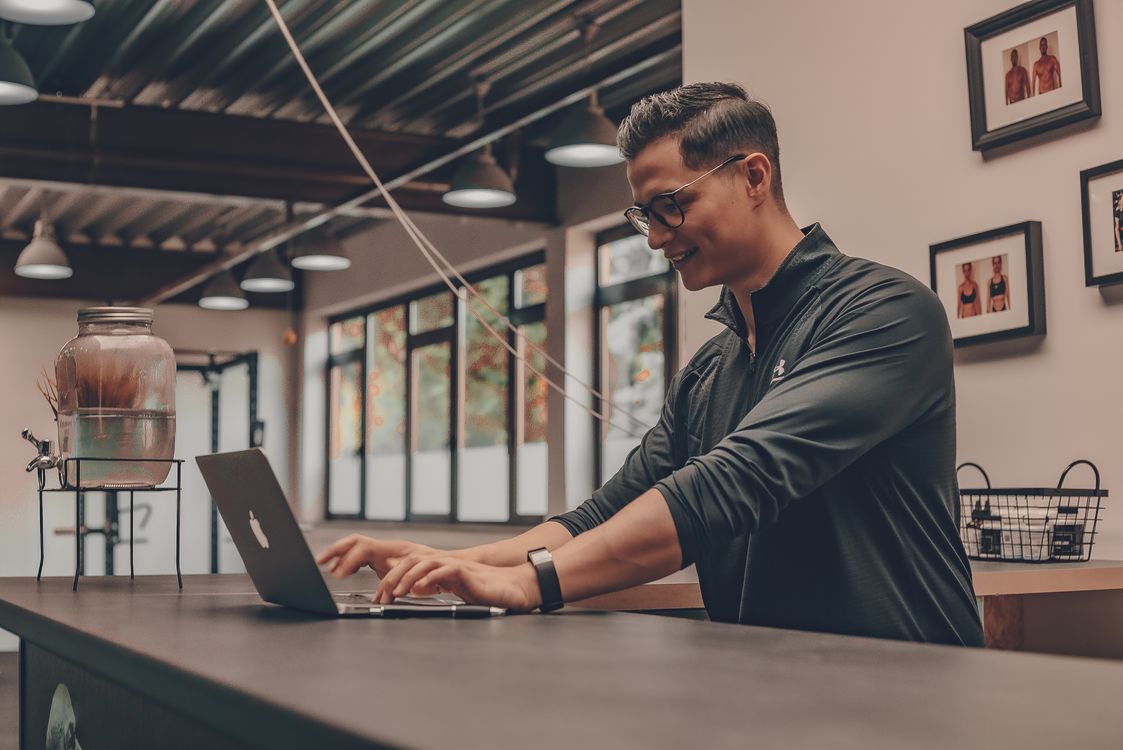 Trainer in sportswear reviewing a laptop in a gym
