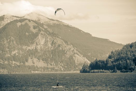 Grayscale Photo of Person Kitesurfing Near the Mountains 
