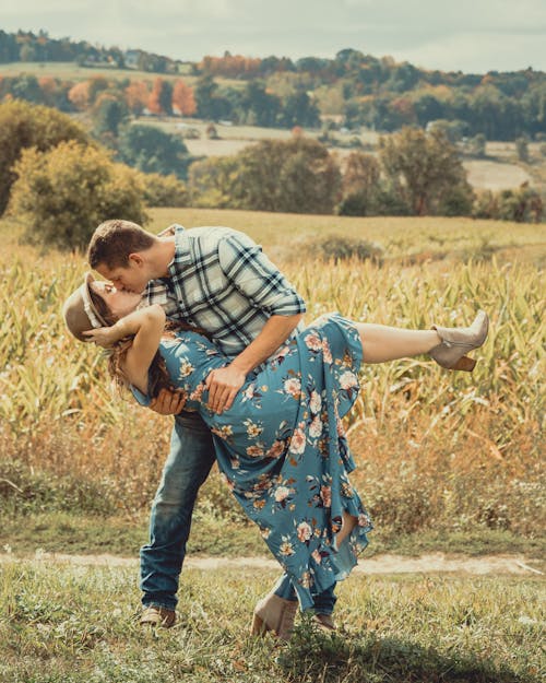 Free A Couple Kissing while Standing on Grass Field Stock Photo