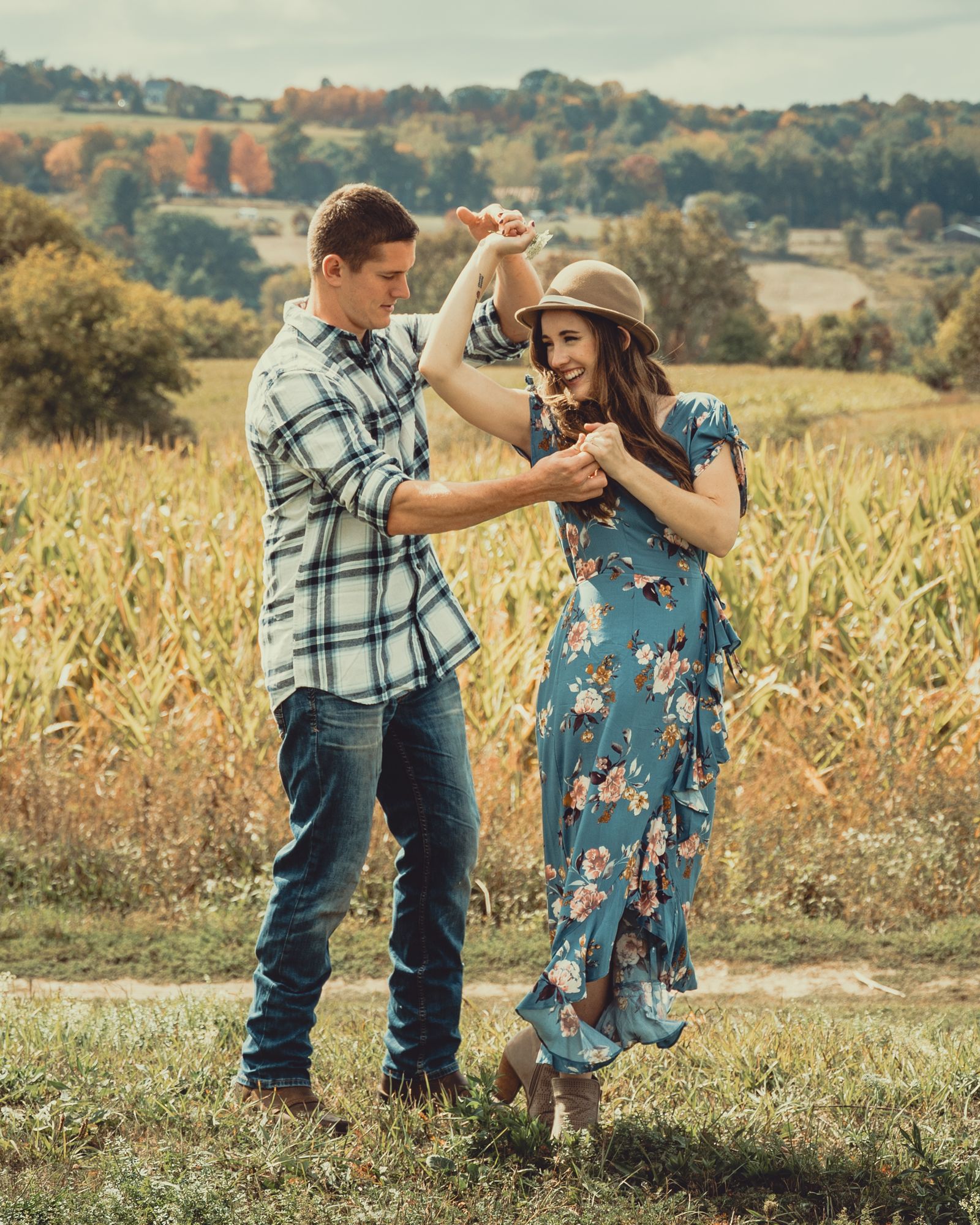 Two-Step — country couple in plaid and hat dancing in an autumn field. Stock photo.