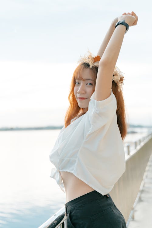 A Woman Wearing White Top and a Flower Crown while Raising Her Hands