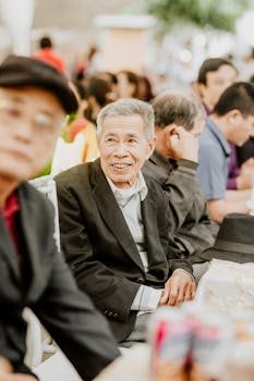 Elderly man smiling joyfully in a lively gathering, creating a warm atmosphere.