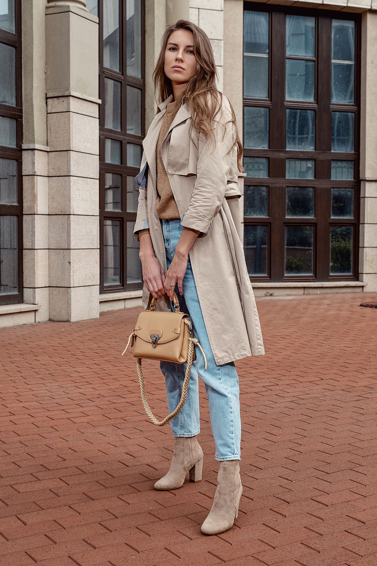 Woman in a beige trench coat with light-wash jeans and ankle boots