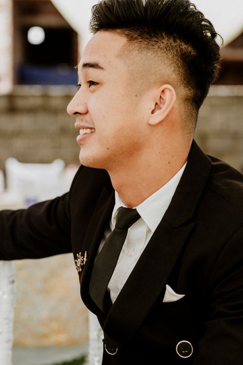 Free Portrait of a young man in a suit smiling, dressed for a formal event. Stock Photo