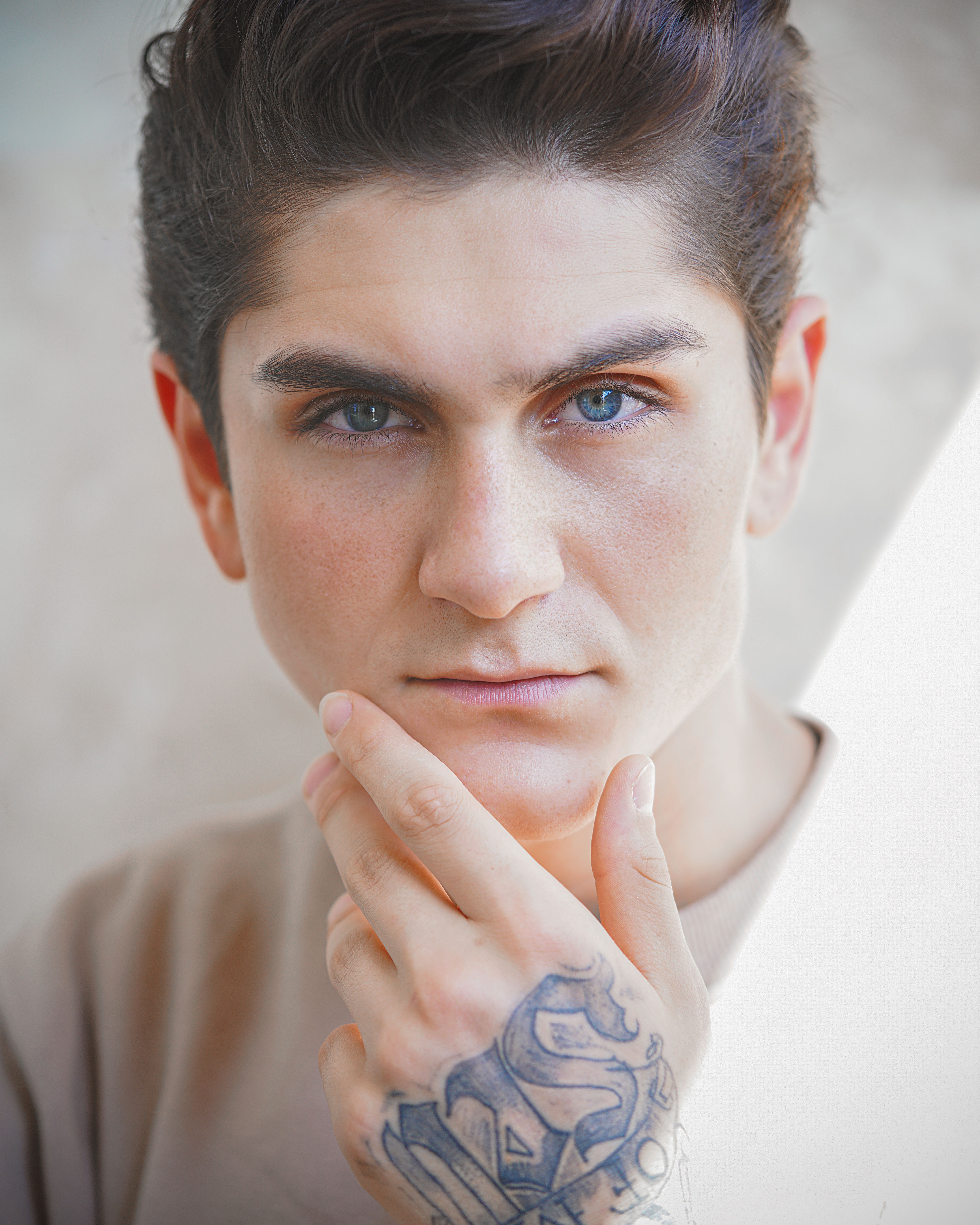 Close-up portrait of a young man with an intense gaze and a tattooed hand on his face, in Tehran.