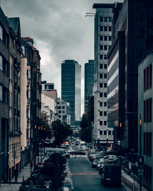 Free A moody street scene in Warsaw, Poland with tall skyscrapers and parked cars. Stock Photo