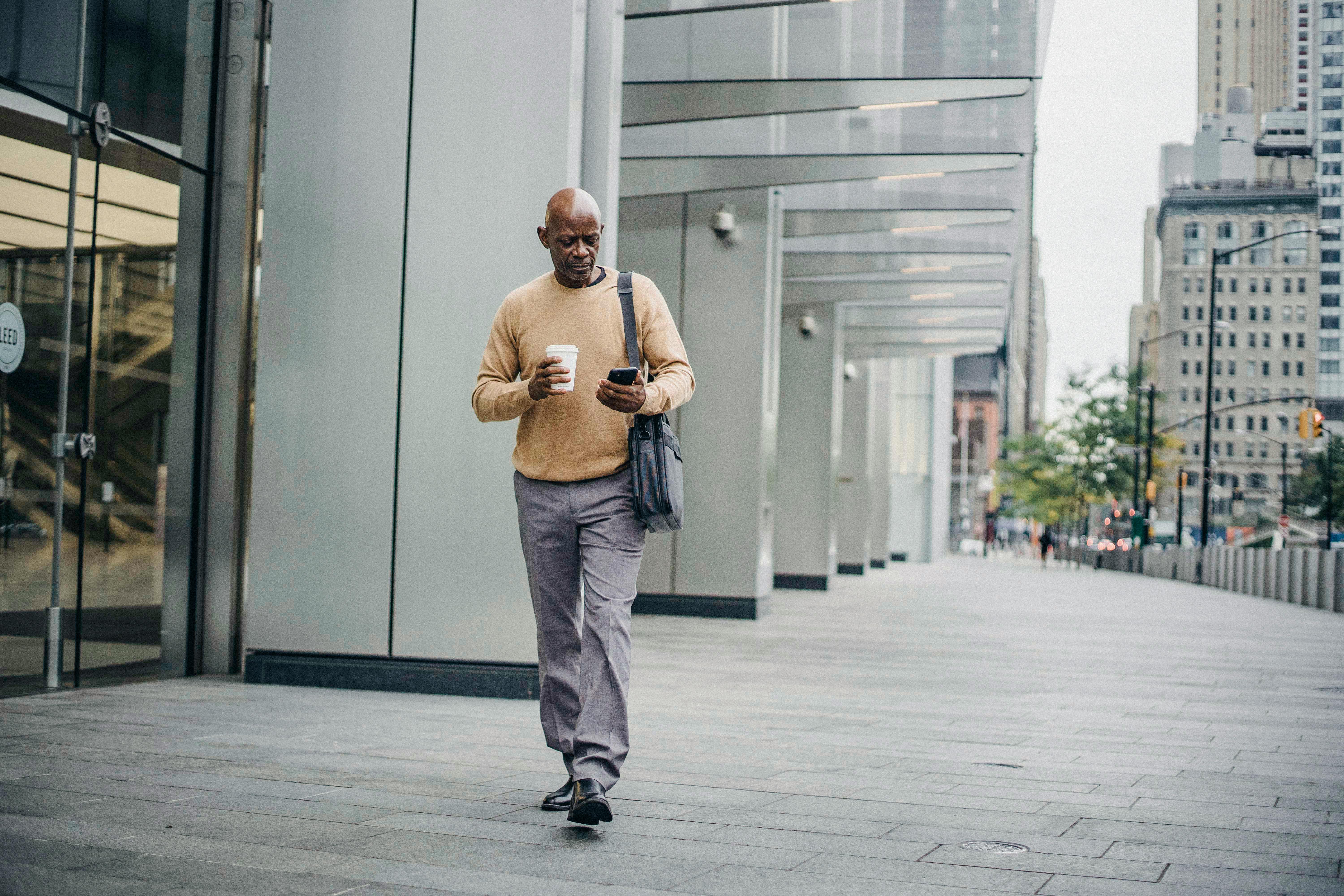 elegant black man with coffee and phone in downtown