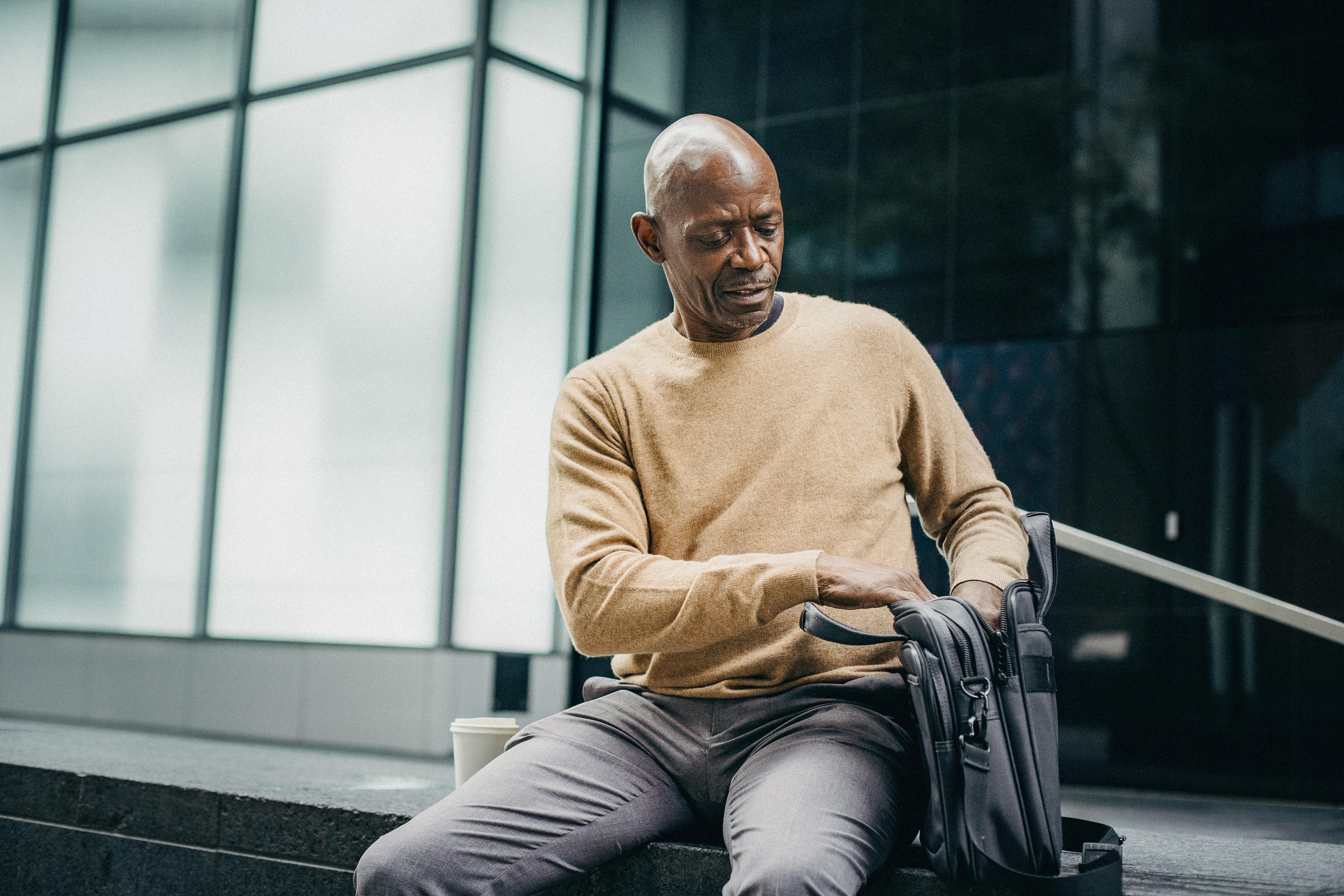 ethnic businessman with bag on street bench