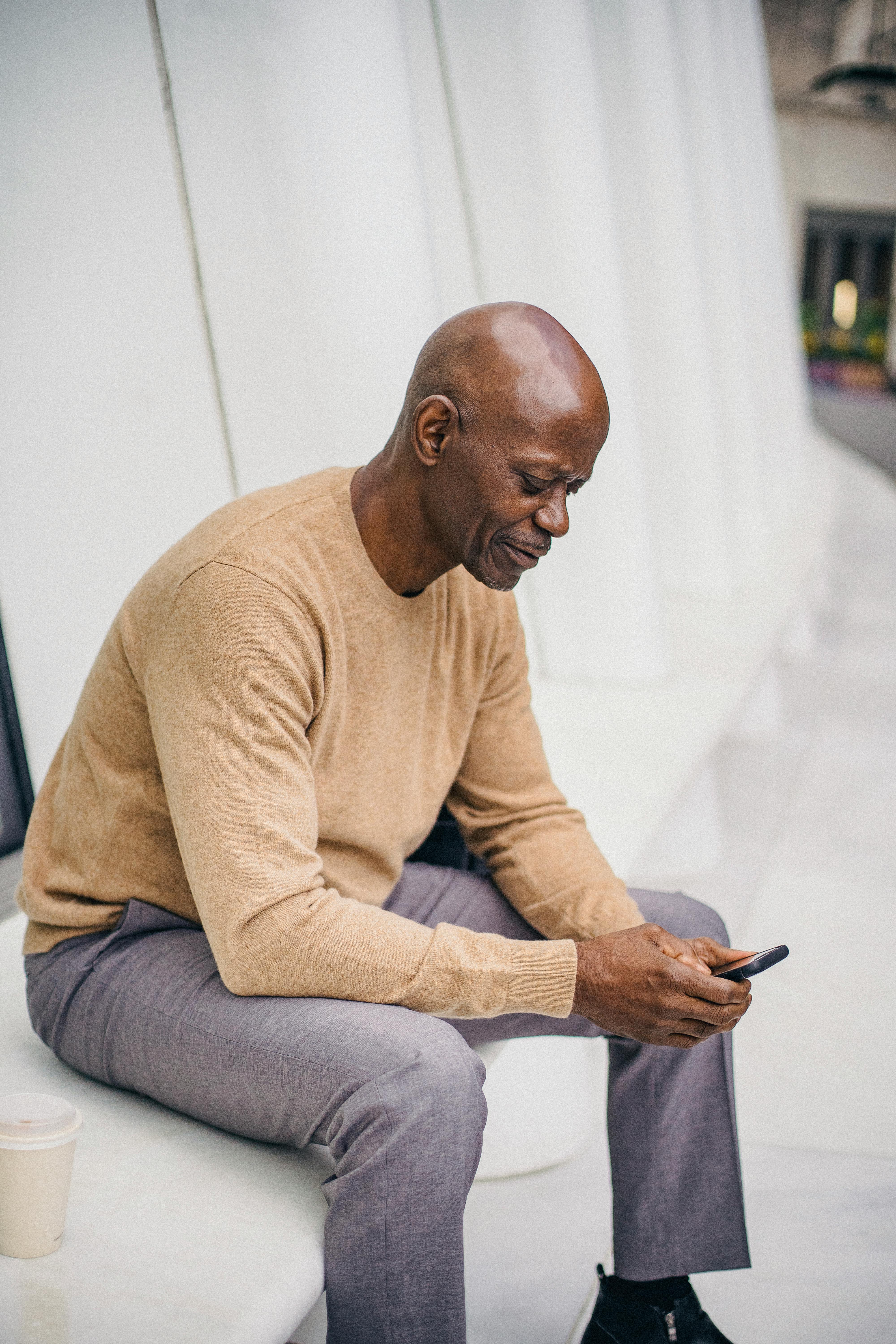 focused black elegant man texting on phone