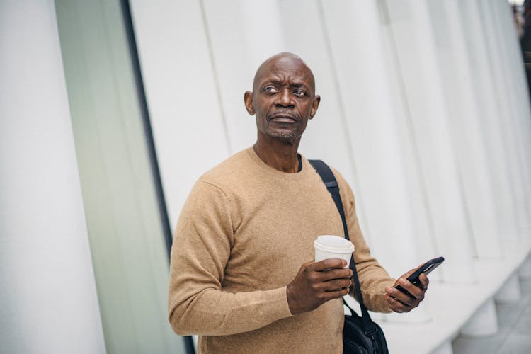 Focused Black Businessman With Phone On Street