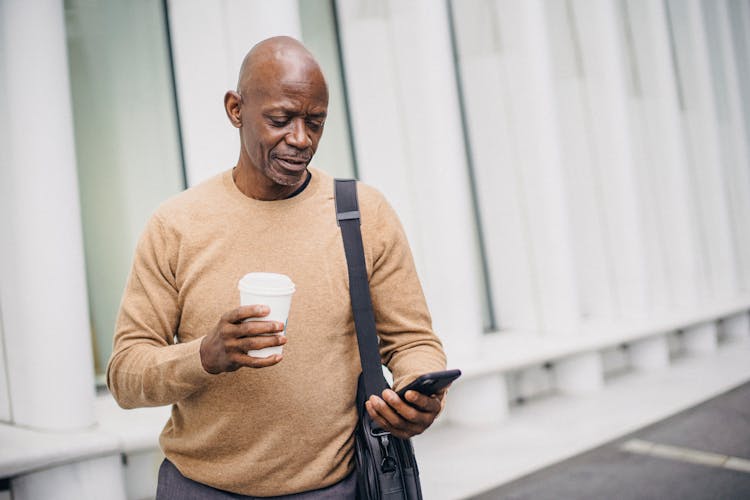 Content Ethnic Businessman Texting On Phone In City