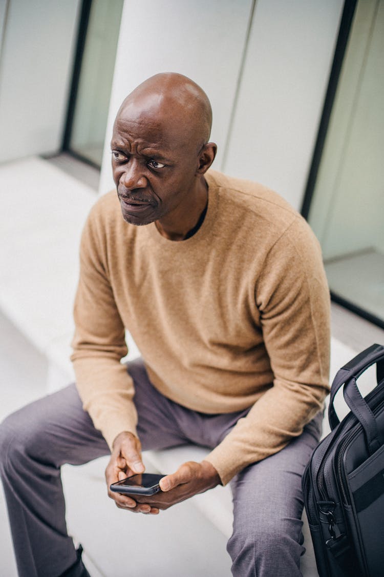 Serious Black Businessman With Phone On Bench