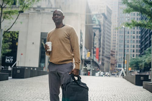 Free Focused black businessman with coffee and bag in city Stock Photo