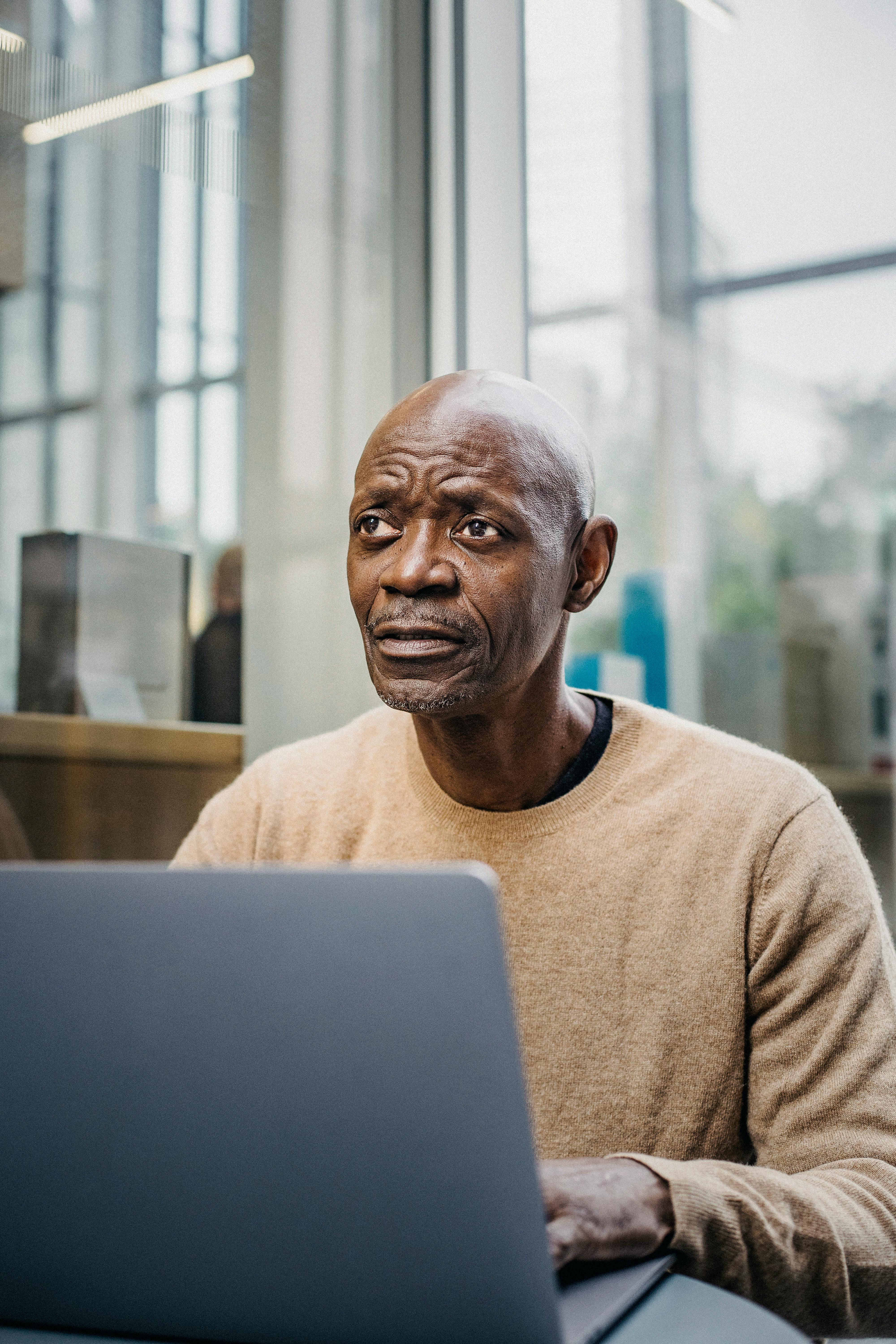 pensive mature businessman working on laptop in cafe