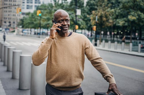 Black man speaking on phone near road