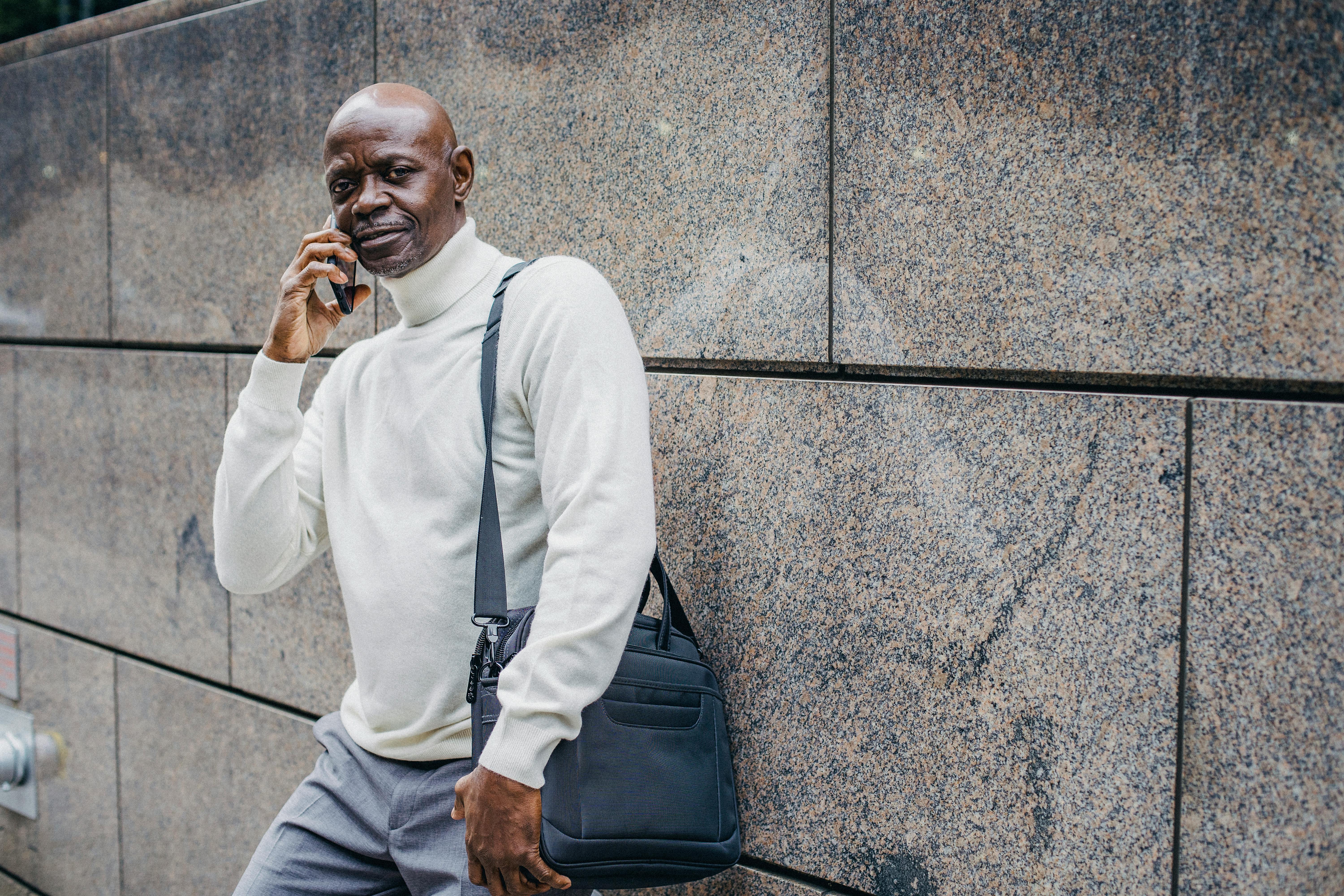 black man speaking on phone near wall