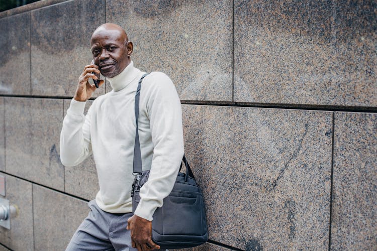 Black Man Speaking On Phone Near Wall