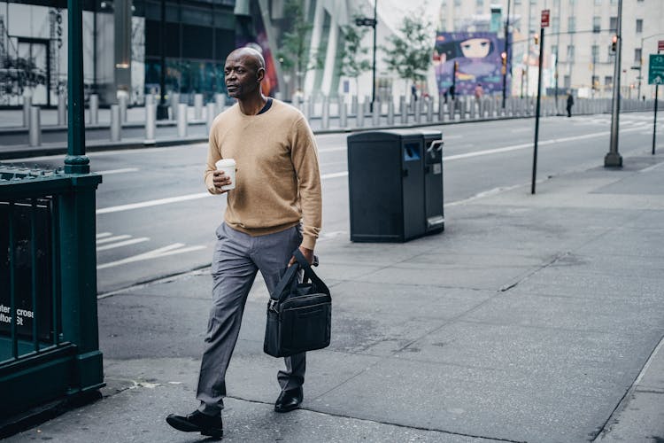 Serious Black Man Walking On Sidewalk With Coffee