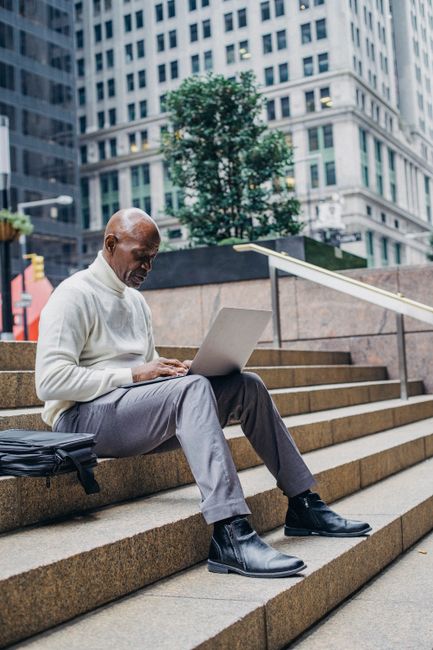 Practical Steps To Automate Compliance Management For Smbs 5 - Automate Compliance,Smbs,How To Automate Compliance Management Processes For Smbs - - Bonelli Systems Full Body Of African American Man In Formal Wear Sitting On Stairs In Downtown And Browsing Netbook During Work