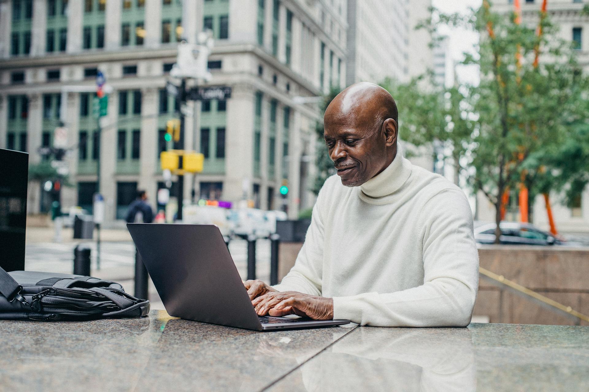 Smiling black man with laptop on street