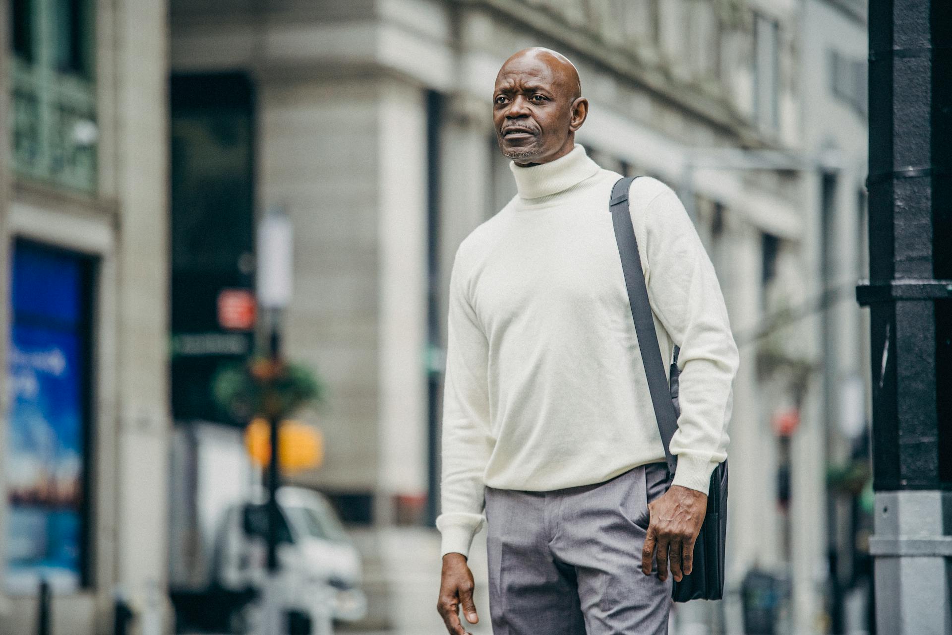 Low angle of confident African American businessman in trendy outfit standing on street in downtown