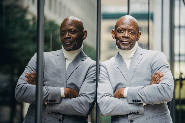 Serious Black Businessman Leaning On Glass Wall