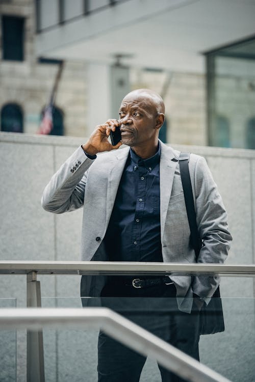 Занятый черный менеджер разговаривает по телефону на улице